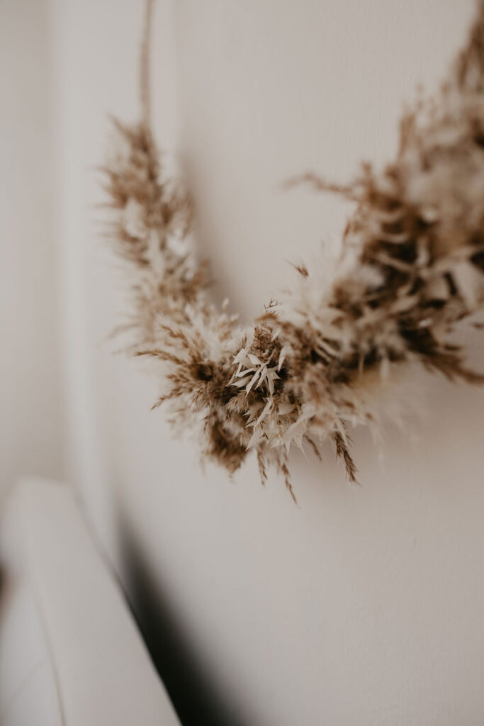 Detailaufnahme eines Trockenblumenkranzes welche über dem Sofa im Fotostudio hängt.